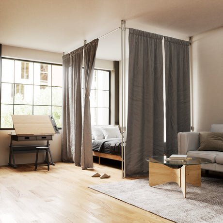 Bedroom with a sheer curtain and blackout curtain hung on a ceiling-mounted room divider rod beside a bed and window